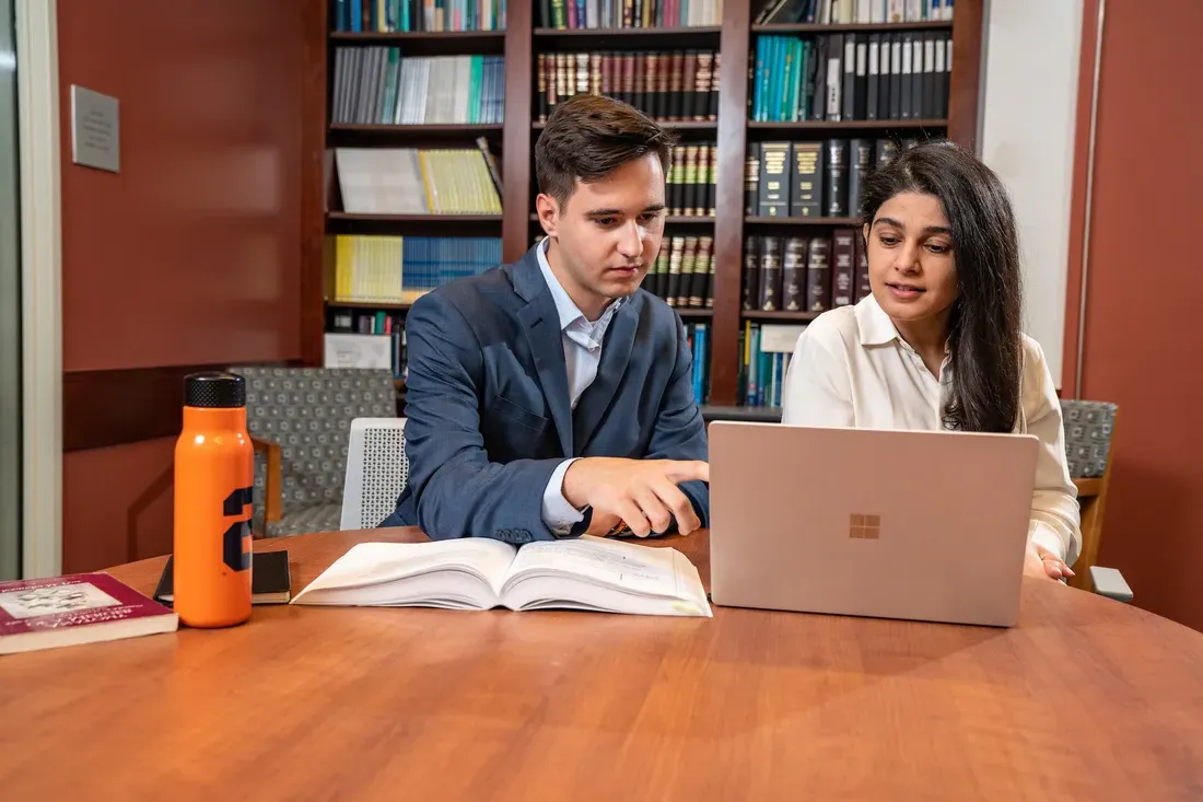 Students using a laptop and textbook.