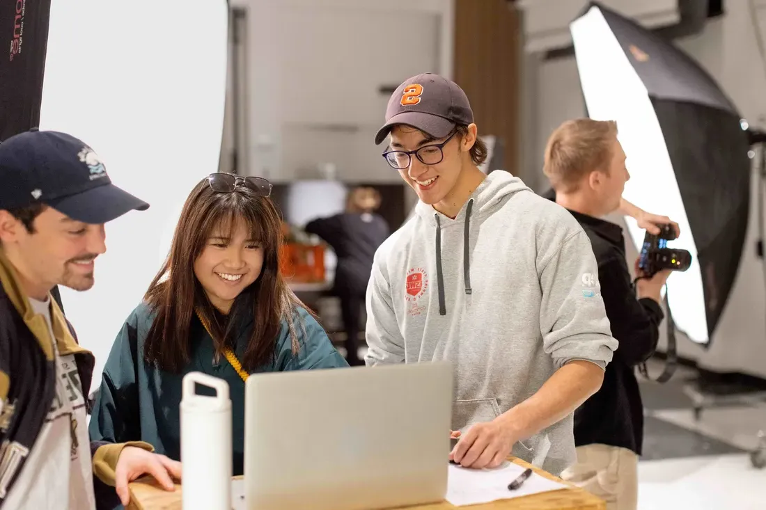 Three Newhouse students working together on a computer.